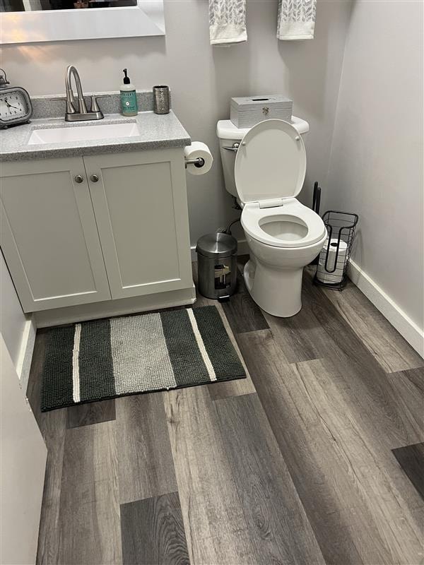 Finished bathroom with vanity, toilet, and wood-look flooring