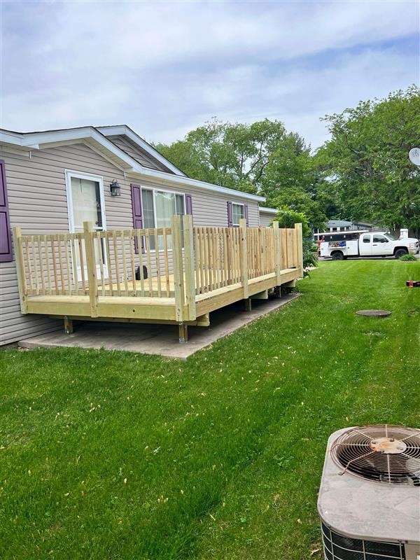 Newly built wooden deck with railings beside a home