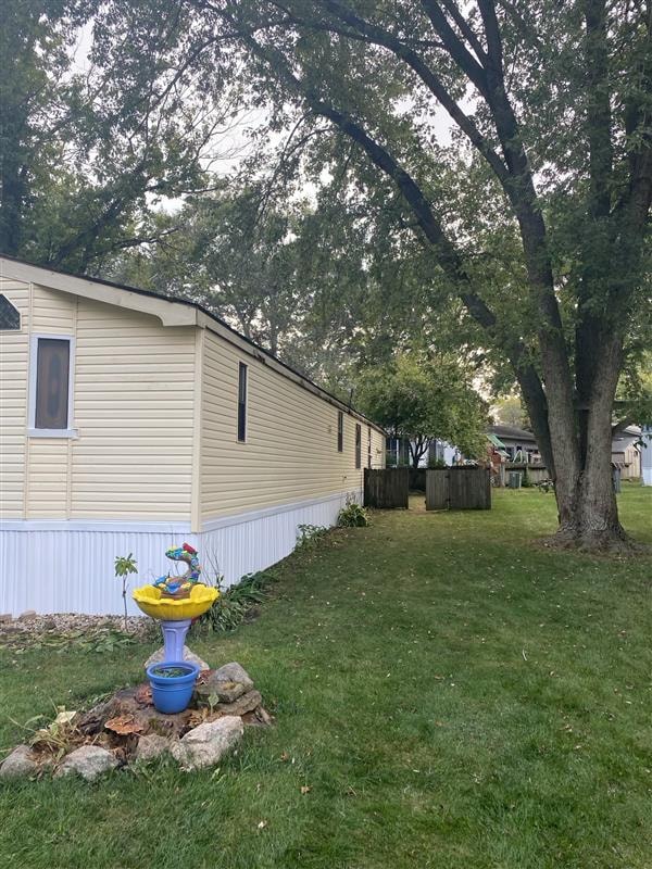 Cream-colored mobile home with vinyl skirting in a tree-lined yard
