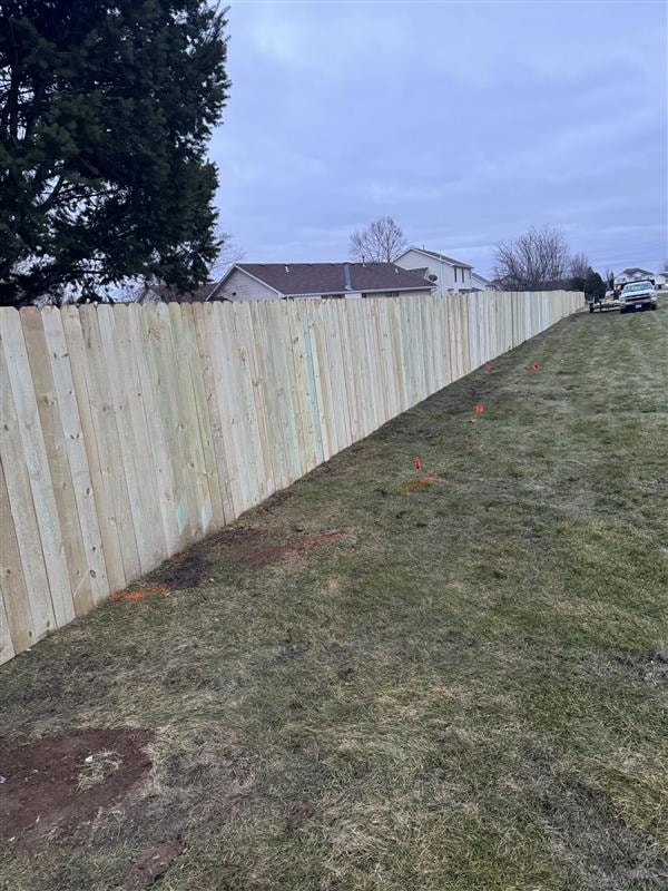 Newly installed wooden privacy fence along a grassy yard